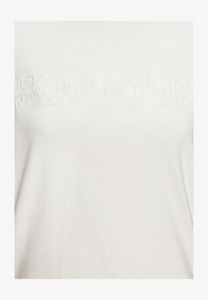 Biela látka s vyvýšenými vyšívanými písmenami hláskujúcimi "BONJOUR", ozdobená malými kvetinovými vzormi.