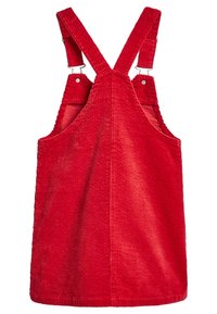 Robe salopette en velours côtelé rouge avec larges bretelles, clips en métal et tissu texturé. Présente une coupe décontractée et sans poches.