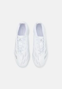 Witte sportieve schoenen met een slank ontwerp, voorzien van een gestructureerde bovenkant, meerdere ventilatiegaten en tonale veters. Zilveren logo-accenten.