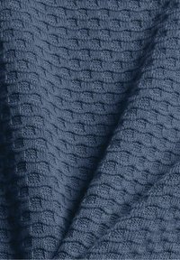 Tissu tricoté bleu foncé avec un motif texturé de carrés en relief répétés et des plis doux.