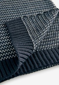 Uldtrøje med et struktureret, houndstooth-mønster i mørk marineblå og lyseblå. Har en ribbet, ensfarvet marineblå kant og foldet kant.