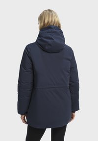 Marineblauwe gewatteerde jas met een capuchon, met een getailleerde taille, lange mouwen en een gladde textuur. Achteraanzicht met een minimalistisch ontwerp.