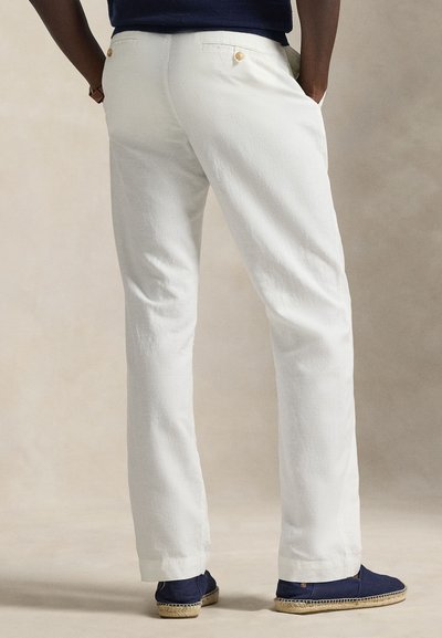Άσπρο λινό παντελόνι με ίσια γραμμή, με δύο πίσω τσέπες και χρυσά κουμπιά, σε συνδυασμό με ναυτικά εσπαντρίγιες.