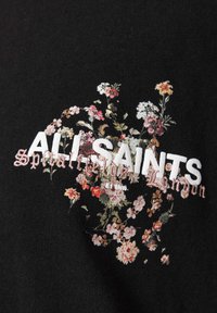 Μαύρο ύφασμα με λευκό κείμενο "ALL SAINTS", με επίστρωση από ένα σύμπλεγμα μικρών ροζ και λευκών κεντημένων λουλουδιών και ξεθωριαστό χειρόγραφο κείμενο.