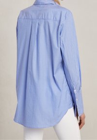 Modrá a bílá pruhovaná košile, dlouhé rukávy, zakulacený lem, detail zadní sklady, manžety na knoflíky, lehký materiál se hladkým povrchem.