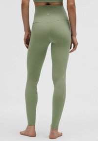 Legginsy do jogi z wysokim stanem, elastyczne, w jednolitym oliwkowym kolorze, z gładkim wykończeniem, dopasowanym krojem oraz małym logo na tylnym pasku.