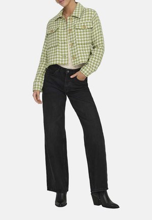 Veste cropped à motif pied-de-poule vert et blanc avec deux poches poitrine, associée à un jean noir taille haute et des bottines à talons noires.