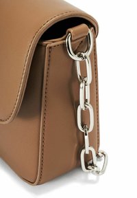 Brązana skórzana torebka w rogu z klapą i srebrnym metalowym łańcuszkiem przypiętym do skórzanej pętli.
