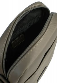 Borsa a tracolla in tessuto grigio con texture, interno foderato in nero, dotata di chiusura con zip e una piccola tasca esterna.