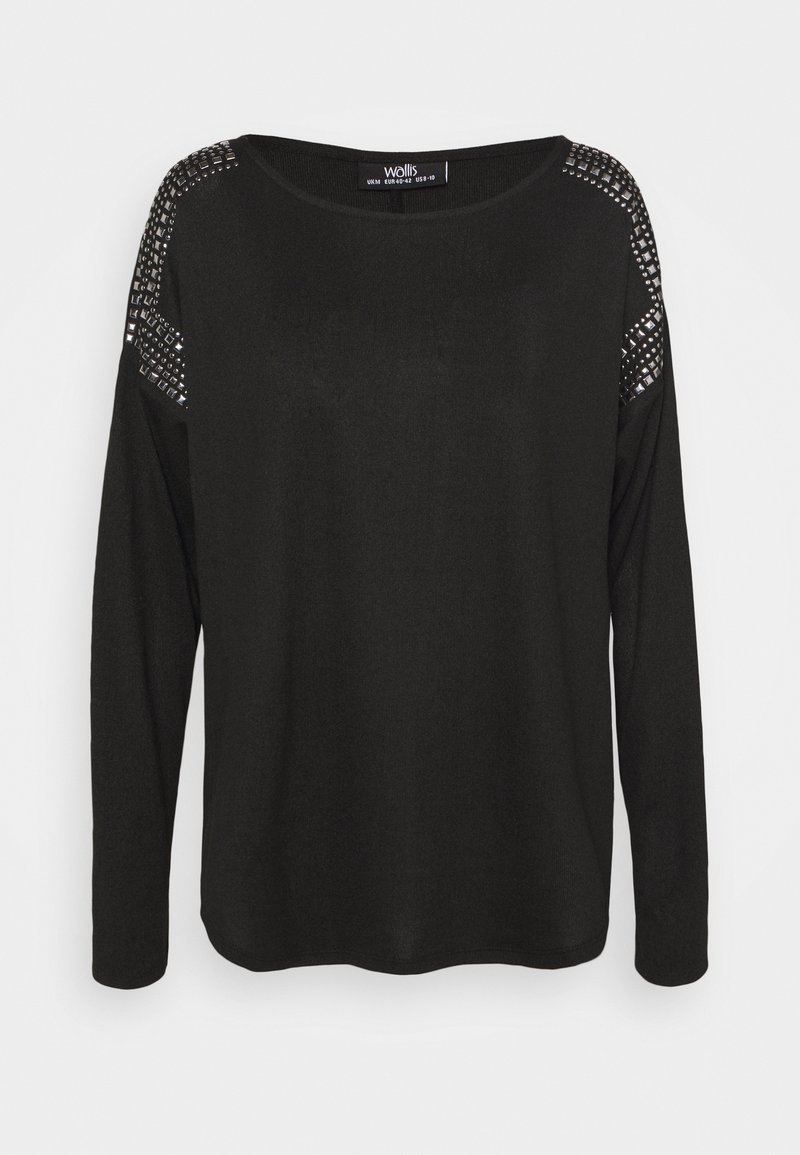 Musta pitkähihainen pusero pyöreällä pääntiellä, jossa on niitattuja yksityiskohtia hartioilla ja pehmeä, teksturoidu kangas.