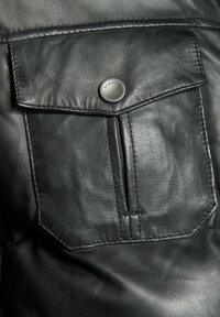 Zwarte leren jas met een knoopsluiting flapzak, een gladde textuur en zichtbare stiksels. Verfraaid met een ronde metalen knoop.