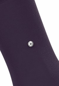 Ingrandimento di una calza viola scuro con un piccolo logo argentato di lato, che mette in evidenza un tessuto testurizzato.