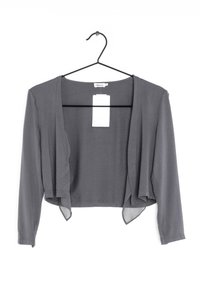 Šedý zkrácený kardigan s dlouhými rukávy, měkkou texturou, otevřeným designem vpředu a připevněnou štítkem, visící na černém háčku.