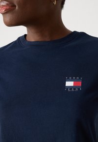 Mørkeblå bomulds T-shirt med rund halsudskæring og et lille logo i rød, hvid og blå, der viser "TOMMY JEANS" på brystet.