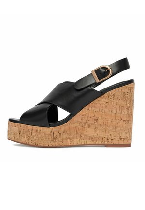 Sandalo nero con zeppa aperta alluce, con piattaforma in sughero, cinturini incrociati in pelle e cinturino alla caviglia con fibbia dorata.