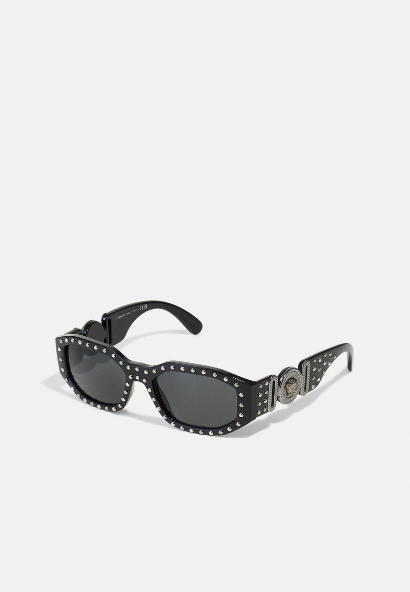 Black sunglasses with rectangular lenses, studded accents around the frames, and a circular hardware detail on the temples. Texture is smooth.