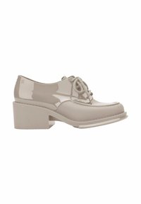 Scarpa oxford in pelle verniciata beige con punta tonda, lacci texture e tacco spesso a blocco. Presenta dettagli cuciti e una finitura lucida.
