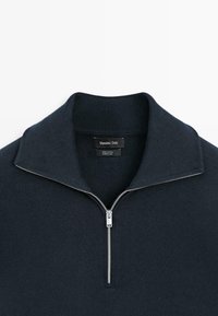 Pull en maille bleu marine foncé avec une demi-fermeture éclair argentée et un col montant, étiqueté Massimo Dutti, fabriqué en 100 % coton.