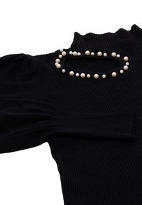 Pulover negru din tricot cu model cu striații, caracterizat printr-un guler înalt și mâneci pufoase. Decorat cu o aranjare circulară de perle albe la guler.