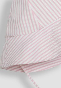 Tissu rayé rose et blanc avec une finition douce et texturée. Il présente un design courbé et superposé avec un lien à la partie inférieure.
