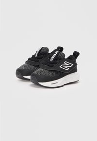Des chaussures de sport noires avec une tige texturée, présentant des lacets élastiques, un col rembourré et une semelle Fresh Foam blanche. Le design comprend un logo sur le côté.