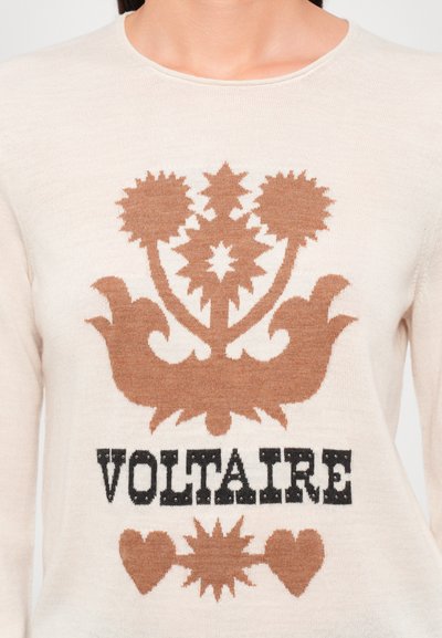 Ljusbeige tröja med brunt stickat blommönster och texten "VOLTAIRE" i svart. Rundad halsringning och mjuk textur.