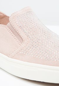 Baskets légères rose pâle à enfiler avec des ornements en strass et une semelle en caoutchouc blanche, dotées d'un panneau latéral élastique pour un enfilage facile.