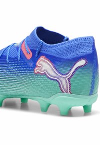 Scarpa da calcio Puma blu e verde con collo in maglia alla caviglia, lacci e tacchetti sulla suola verde menta.