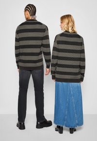 Sweter w paski, w ciemnoszarym i czarnym kolorze, o luźnym kroju. W połączeniu z ciemnymi dżinsami oraz niebieską spódnicą dżinsową, pokazującymi różnorodność faktur.