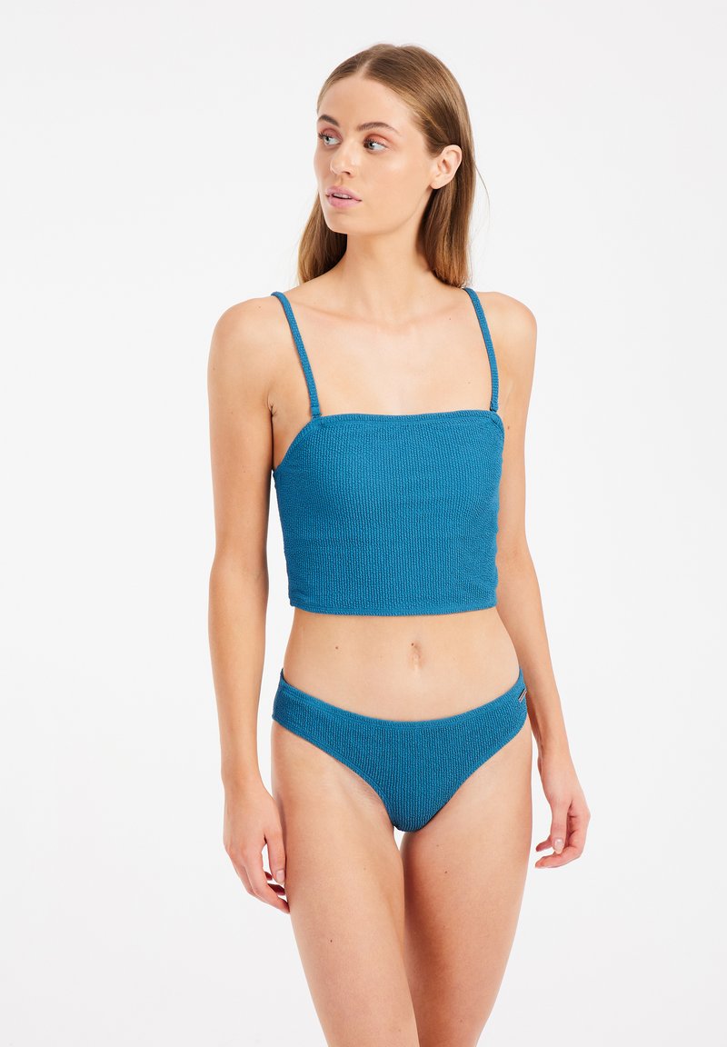 Set di bikini a coste di colore teal con reggiseno a scollo quadrato e spalline sottili, abbinato a slip a vita bassa. Spalline regolabili per una vestibilità perfetta.