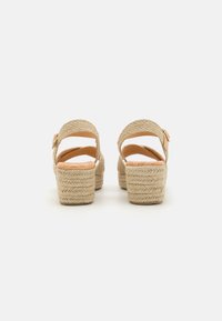 Sandali espadrille beige con texture intrecciata, apertura sul retro, cinturino alla caviglia regolabile e tacco a piattaforma spesso.
