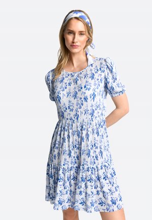 Rochie florală în tonuri de alb și albastru, cu mâneci scurte bufante, decolteu rotund și fustă în straturi cu textură volanată.