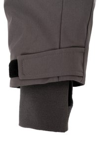 Pelēka auduma bikses ar strukturētu apdari, kurām ir melna velcro siksna un kontrastējoša tumši pelēka iekšējā odere.