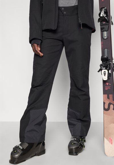 Black ski pants made of durable fabric, featuring a straight cut, reinforced knees, and gray accents. Paired with black ski boots and a snowboard.