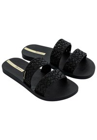 Des sandales noires à glissière disposent de deux straps tissés et d'une semelle texturée avec un motif en nid d'abeille. Accent logo doré sur le côté.