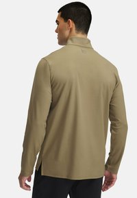 Langärmliges Hemd in Khaki, aus glattem Stoff gefertigt. Verfügt über einen Stehkragen und Seitenschlitze am Saum für zusätzliche Bewegungsfreiheit.