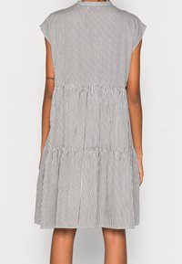 Zwart-wit gestreepte jurk met korte mouwen, met een gelaagde uitstraling en een geraffineerde taille, gemaakt van een lichtgewicht stof en voorzien van zakken.