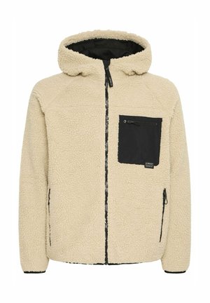 Beige fleece jakk, millel on must lukuga rinnatasku, mustad lukud ja kapuuts. Tekstureeritud pind ja lõdva istuvuse kujundus.