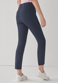 Marineblauwe broek met een slim fit, elastische tailleband en twee achterzakken. Gemaakt van een soepele stof, gecombineerd met witte sneakers.