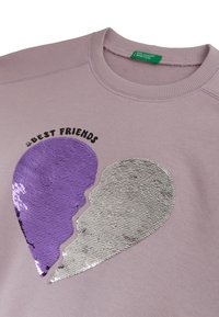 Felpa viola chiaro con un design di cuore spezzato in paillettes viola e argento e il testo "Migliori Amiche" sopra il cuore.