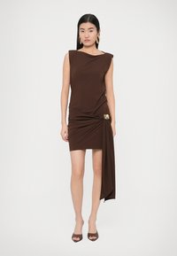 Pruun kehasse vormis kleit venivast kangast, millel on asümmeetriline volang, rõhuasetus puusal ja varrukateta disain.