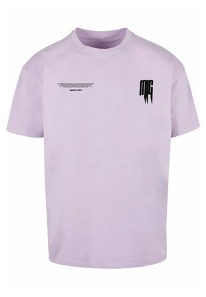 T-shirt lavande à manches courtes et col rond avec petit texte noir et logo stylisé « MG » sur le haut de la poitrine.