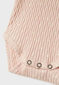 Rosa ribbet stoff med hvite prikker, med trykknapp-lukking nederst. Myk tekstur og milde kurver i designet.