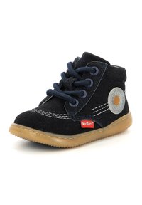 Stivale alla caviglia in suede nero con lacci blu navy, cuciture bianche, suola in gomma e un accento con logo circolare. Presenta un tessuto morbido e un design robusto.