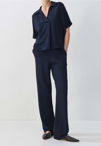 Ensemble assorti bleu marine composé d'une chemise à col à manches courtes ample et d'un pantalon à coupe décontractée, fabriqué dans un tissu doux avec une texture subtile.