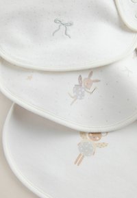 Tre tygband i vitt med subtila prickar. Har broderade motiv av en rosett, en kanin och en björn med vingar. Mjuk textur.