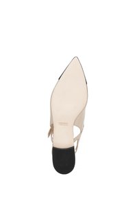 Zapato de tacón alto beige con puntera afilada, laterales cortados y acentos negros. Presenta una parte superior de cuero suave y una suela negra texturizada.