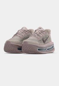 Light pink athletic shoes feature a mesh upper, padded collar, and visible air cushioning in the sole. Textured rubber outsole for grip.