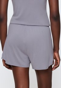 Szare spodenki o gładkiej fakturze i elastycznym pasie, z delikatnymi koronkowymi akcentami na dnie i luźnym kroju.