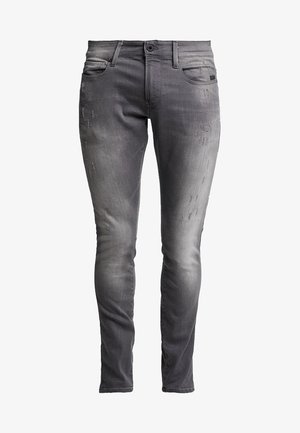 Calças skinny de ganga cinza com um acabamento desbotado, apresentando um desgaste subtil, um design clássico de cinco bolsos e fecho com botão metálico.